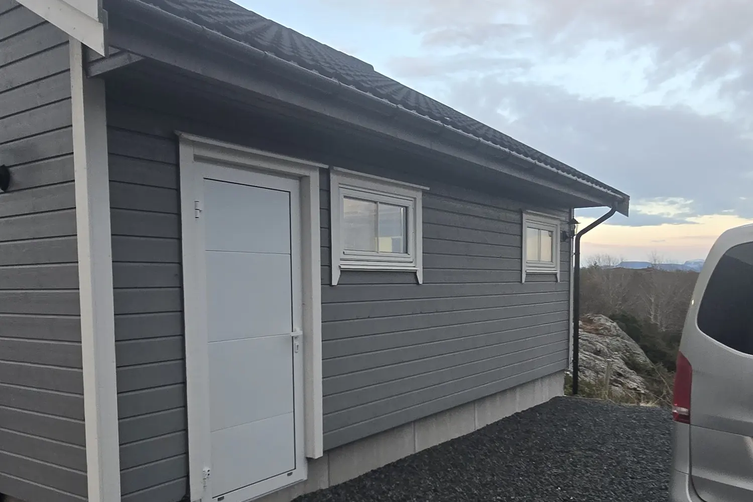 Grå garasje i tre med hvit dør, nymalt utvendig